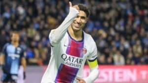 PSG player Achraf Hakimi smiles with raised arm during the match