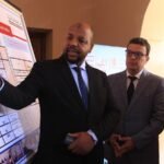 مسؤول يقدم عرضًا توضيحيًا لبرنامج مدارس الفرصة الثانية أمام حضور رسميين