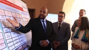 مسؤول يقدم عرضًا توضيحيًا لبرنامج مدارس الفرصة الثانية أمام حضور رسميين