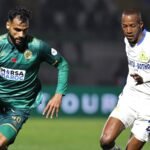 Partido de fútbol con jugador en camiseta verde y jugador en camiseta blanca compitiendo