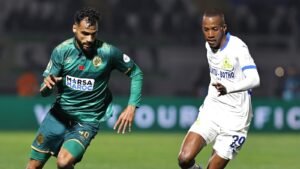 لاعب بقميص أخضر ولاعب بقميص أبيض يتنافسان على الكرة في مباراة كرة قدم