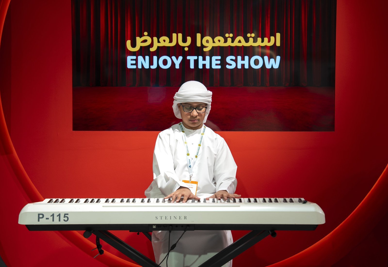 Musician in traditional dress performing keyboard at red stage event