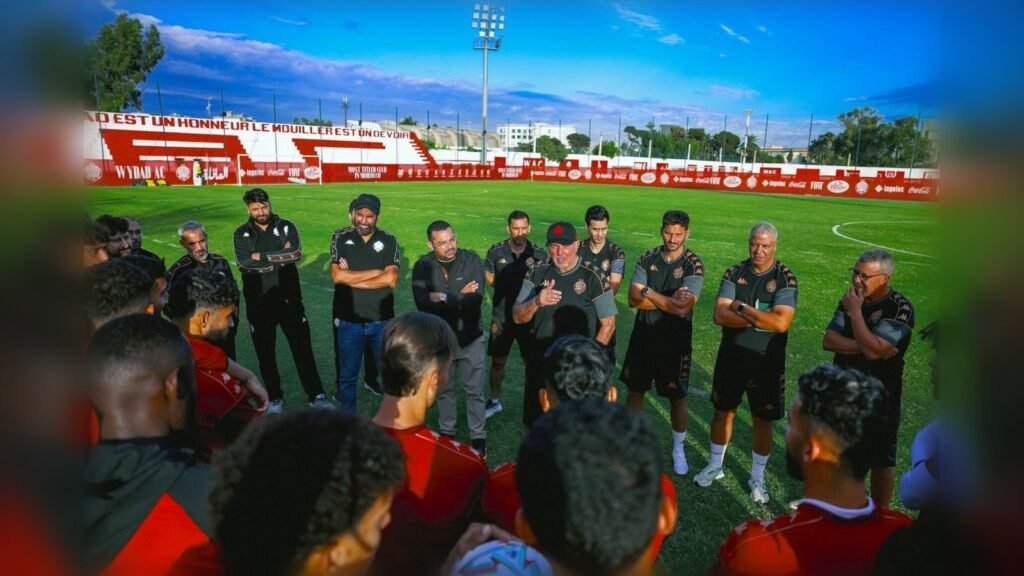 Coaching staff addresses team during training session at football stadium