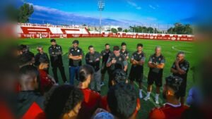 Groupe d'entraîneurs et de joueurs écoutant lors d'une réunion d'équipe au stade
