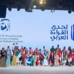 Escenario de ceremonia con pancarta del Desafío de Lectura Árabe y participantes en traje tradicional