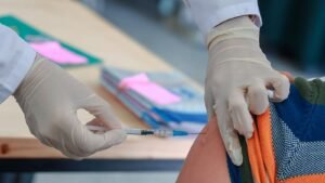 Close-up of gloved healthcare worker administering vaccine injection to patient's arm