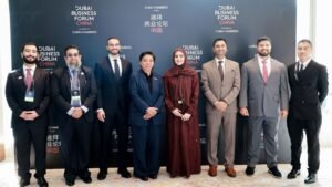 مجموعة من المسؤولين والممثلين أمام لافتة منتدى دبي للأعمال