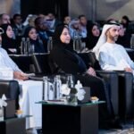 ثلاثة مسؤولين جالسين في الصفوف الأمامية لمنتدى البيانات المالية مع حضور آخرين في الخلفية