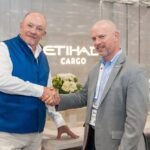 Poignée de main entre deux professionnels dans le bureau d'Etihad Cargo avec fleurs blanches