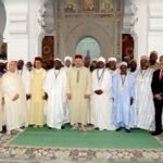 Group of African scholars in traditional Islamic attire inside an ornate mosque