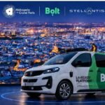 سيارة بيجو بيضاء وخضراء مع شعار Bolt أمام أضواء باريس الليلية