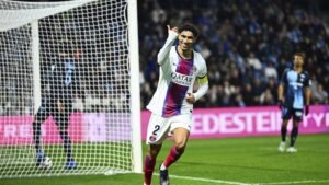 لاعب فريق باريس سان جيرمان بقميص أبيض يحتفل برفع يده