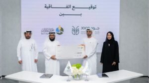 Quatre personnes tenant un gros chèque lors de la signature d'un accord de collaboration