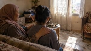 أم تضع يدها على كتف ابنتها المراهقة في المنزل