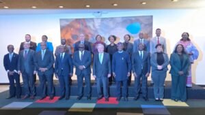 Groupe de responsables debout sur un podium lors d'une réunion multilatérale avec panneau coloré en arrière-plan