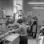 Black and white photo of textile factory workers operating production machinery