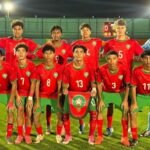 Moroccan youth footballers in red and green uniforms on floodlit pitch