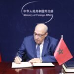 موظف بوزارة الخارجية المغربية يوقّع على طاولة مع أعلام المغرب والصين