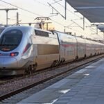 Silver and red Al Boraq train stopped at railway station platform