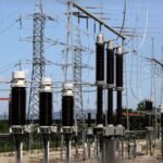 High-voltage electrical station with transformers and metal towers under clear sky