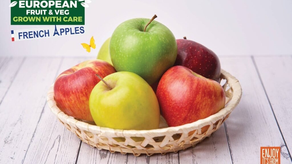 Fresh multicolored apples in woven basket on white wooden table