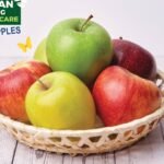 Fresh multicolored apples in woven basket on white wooden table