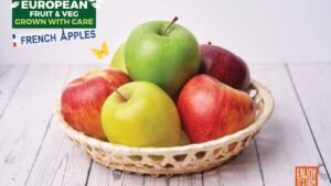 Fresh multicolored apples in woven basket on white wooden table