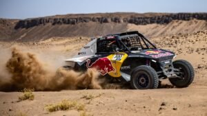 Rally car with Red Bull branding racing through dusty Moroccan desert landscape