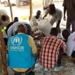 Trabajadores humanitarios con chalecos azules del ACNUR trabajando con refugiados