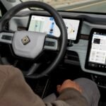 سائق في سيارة Rivian مع شاشات عرض تكنولوجيا القيادة الذاتية والملاحة