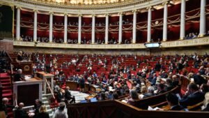 Cámara de la Asamblea Nacional francesa con diputados sentados en escaños rojos durante sesión plenaria