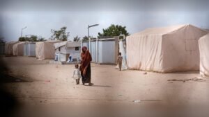 مخيم للاجئين يحتوي على خيام بيضاء وملاجئ مؤقتة مع عائلات نازحة